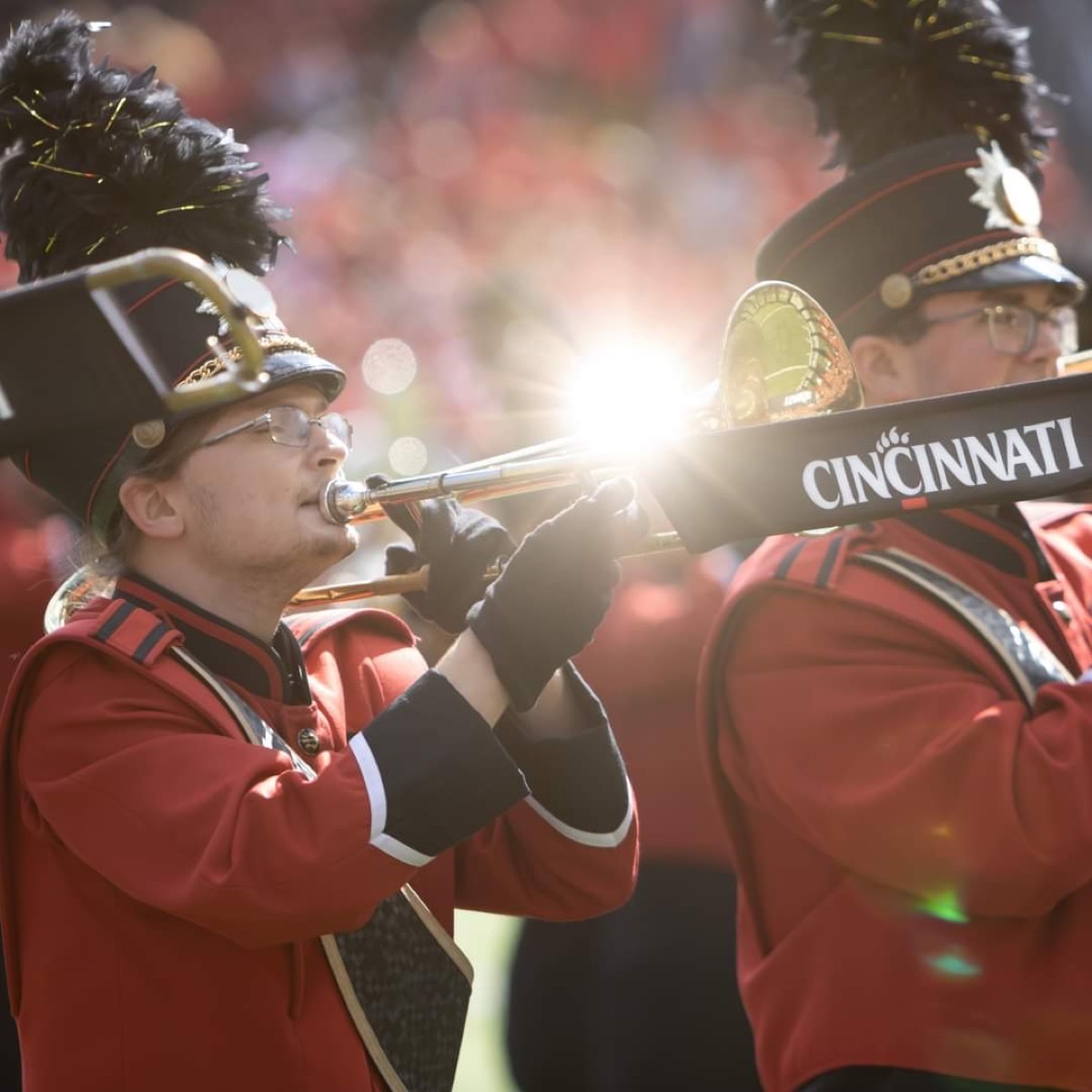 Levi Huff playing trombone with sunlight flare during a University of Cincinnati game performance