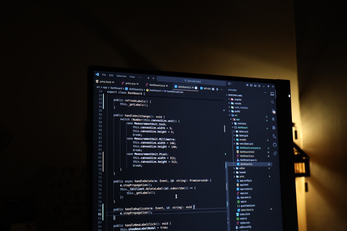 A computer monitor showing source code in a dark mode editor, lit by warm amber light
