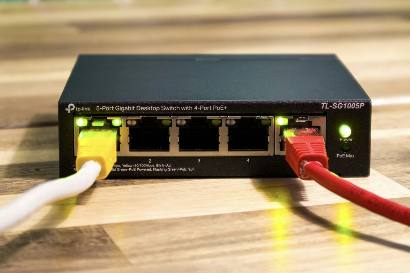 A desktop Ethernet switch with two cables connected and green status lights illuminated