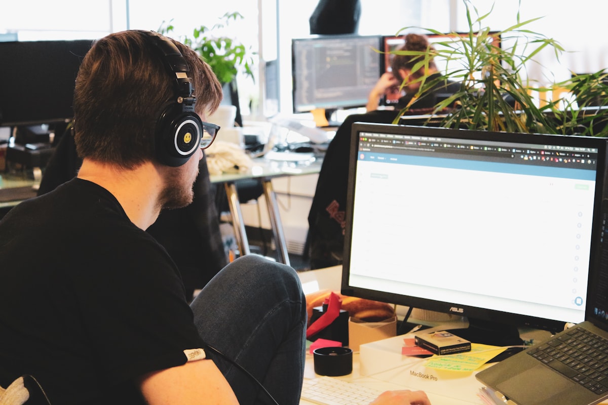 IT support professional wearing headphones at desk with laptop computer