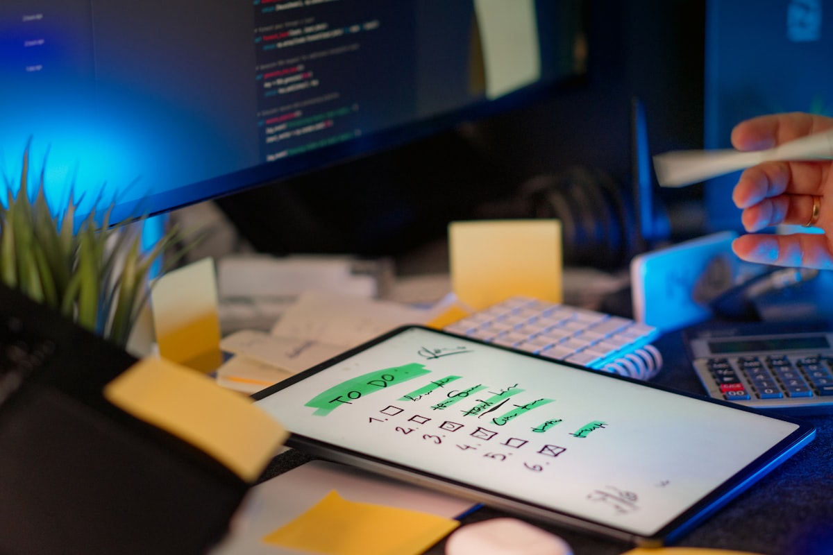 Developer working at desk with multiple computer monitors displaying code and digital interface