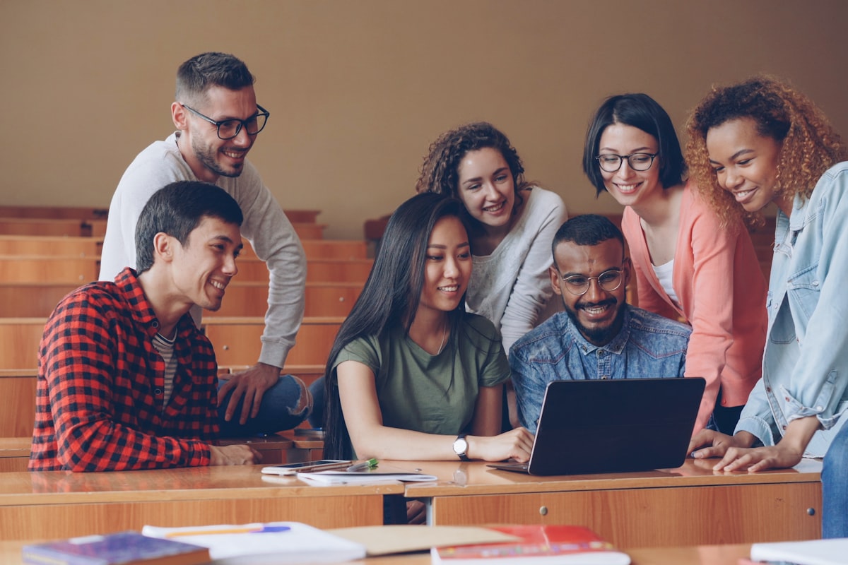 Diverse group of university students gathered around a laptop collaborating together